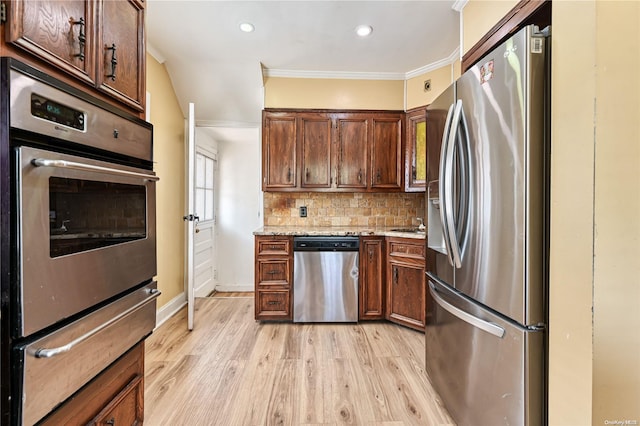 kitchen with crown molding, decorative backsplash, light stone countertops, appliances with stainless steel finishes, and light hardwood / wood-style floors