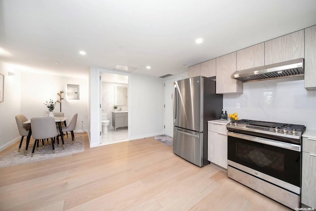 kitchen featuring electric panel, light wood-type flooring, exhaust hood, and appliances with stainless steel finishes