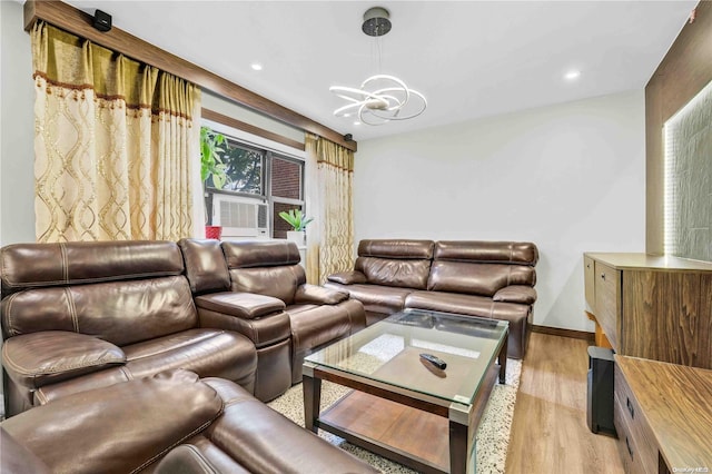 living room featuring cooling unit, light hardwood / wood-style floors, and an inviting chandelier