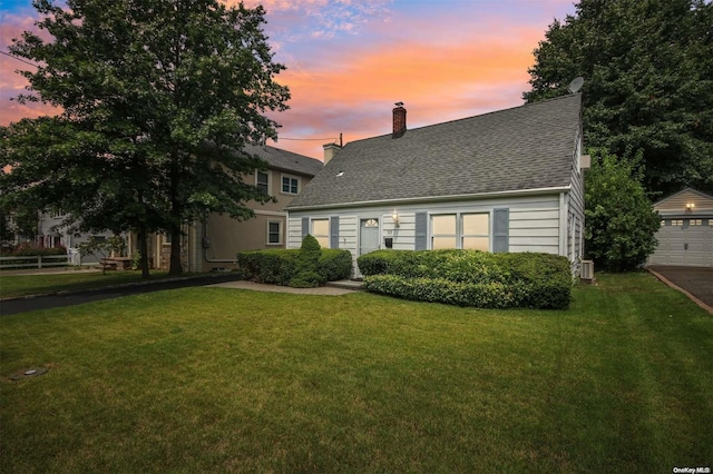 view of front of property featuring an outdoor structure, a garage, and a yard