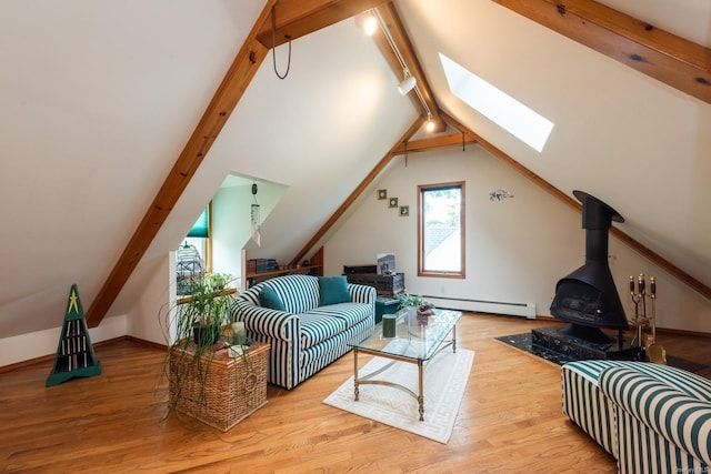 living room with a wood stove, lofted ceiling with skylight, rail lighting, a baseboard radiator, and light hardwood / wood-style floors