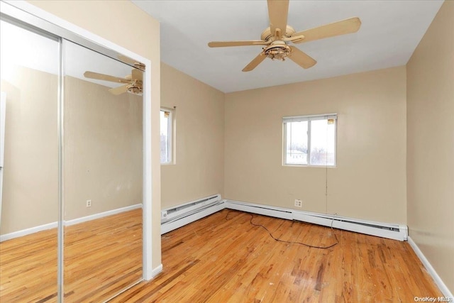 unfurnished bedroom with light wood-type flooring, a closet, a baseboard radiator, and ceiling fan