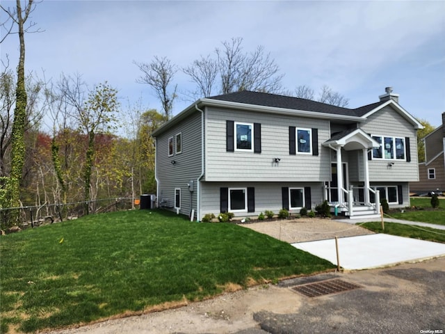 raised ranch with central AC unit and a front lawn