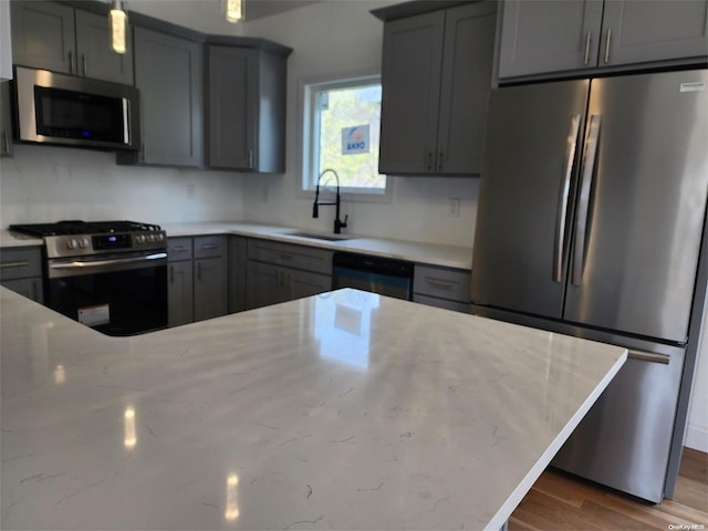 kitchen featuring hardwood / wood-style floors, stainless steel appliances, gray cabinetry, and sink