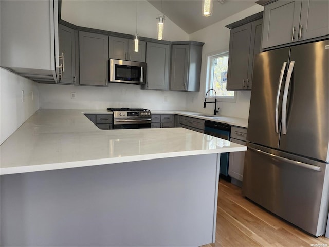 kitchen with hanging light fixtures, kitchen peninsula, light hardwood / wood-style flooring, and stainless steel appliances