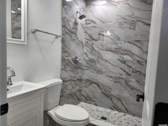 bathroom featuring a tile shower, vanity, and toilet