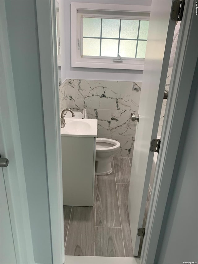 bathroom with vanity, toilet, and tile walls