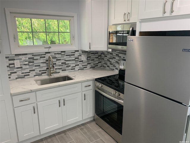 kitchen featuring white cabinets, stainless steel appliances, light stone countertops, and sink