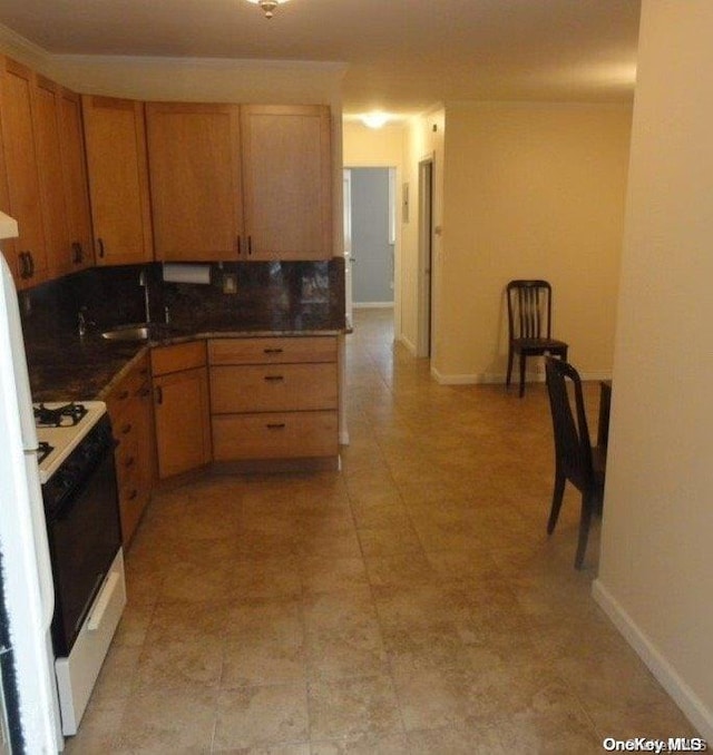 kitchen with white range with gas stovetop, backsplash, and sink