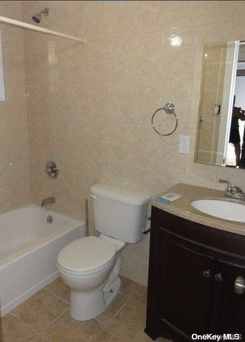 full bathroom with vanity, bathing tub / shower combination, tile patterned flooring, toilet, and tile walls