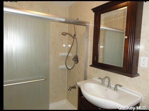 bathroom with tasteful backsplash, an enclosed shower, and sink