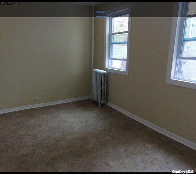 spare room featuring radiator and carpet floors