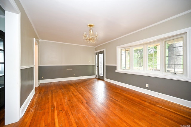 empty room featuring ornamental molding, plenty of natural light, hardwood / wood-style floors, and a notable chandelier