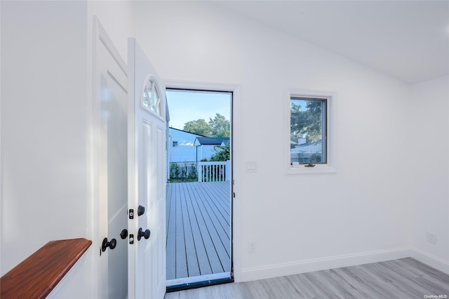 doorway to outside with vaulted ceiling and light hardwood / wood-style flooring