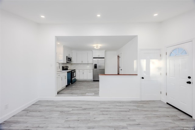 kitchen featuring sink, white cabinets, light wood-type flooring, and appliances with stainless steel finishes