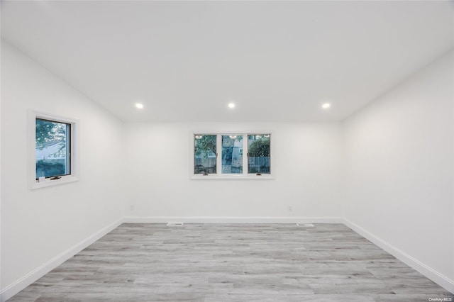 empty room featuring vaulted ceiling, a wealth of natural light, and light hardwood / wood-style flooring