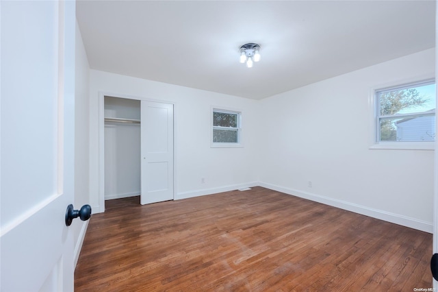 unfurnished bedroom with dark hardwood / wood-style floors and a closet