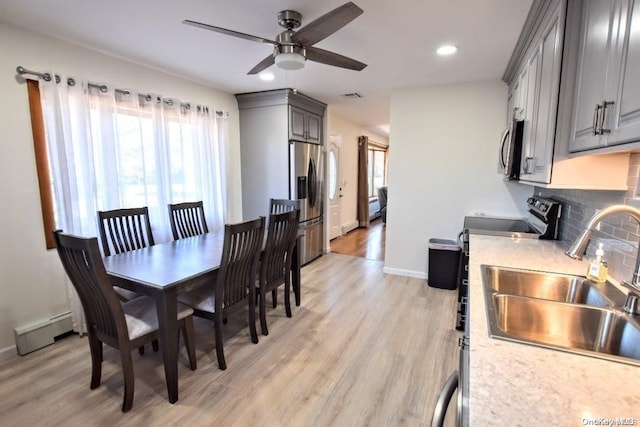 dining room with ceiling fan, light hardwood / wood-style floors, sink, and a baseboard radiator