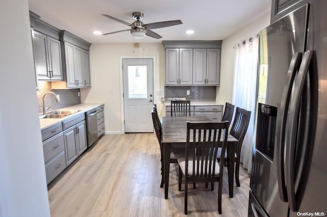 kitchen with sink, ceiling fan, gray cabinets, appliances with stainless steel finishes, and light hardwood / wood-style floors