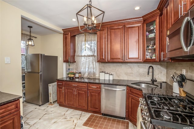 kitchen with decorative backsplash, appliances with stainless steel finishes, dark stone counters, sink, and pendant lighting