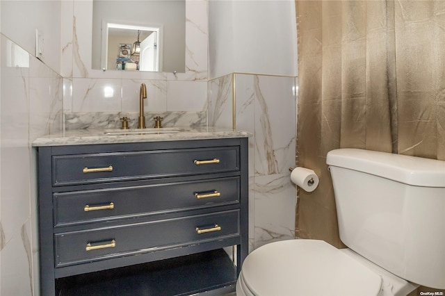 bathroom with vanity, toilet, and tile walls