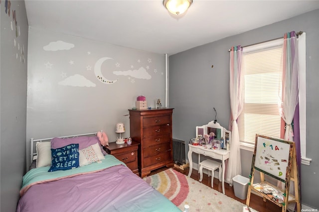 bedroom with radiator and hardwood / wood-style floors