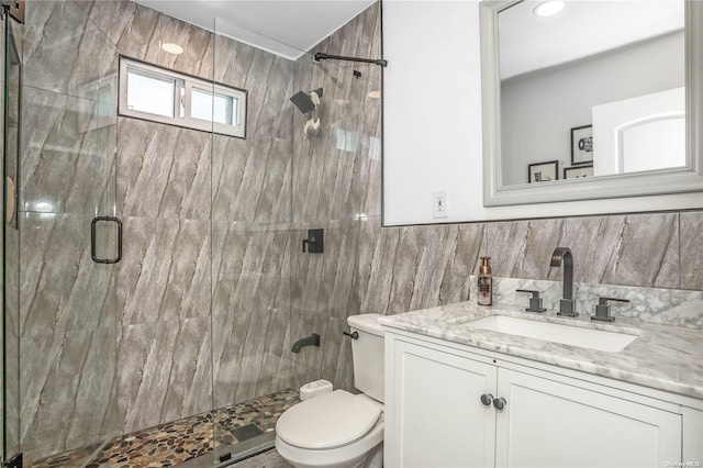 bathroom featuring toilet, vanity, tile walls, and walk in shower