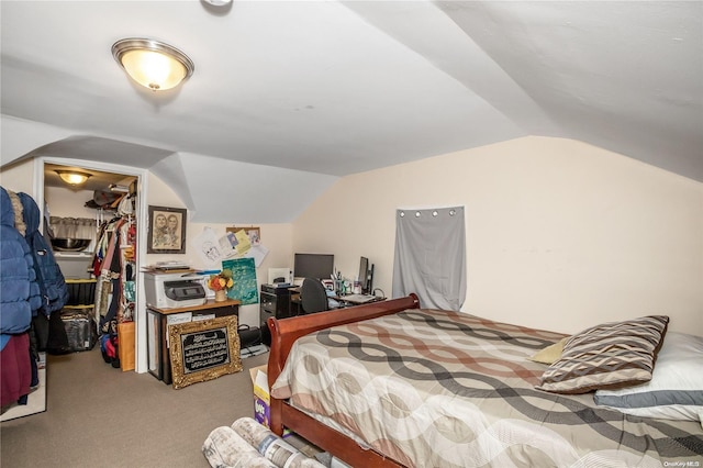 carpeted bedroom with a walk in closet, vaulted ceiling, and a closet