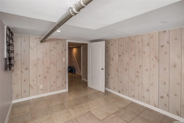 basement featuring wooden walls and light tile patterned floors