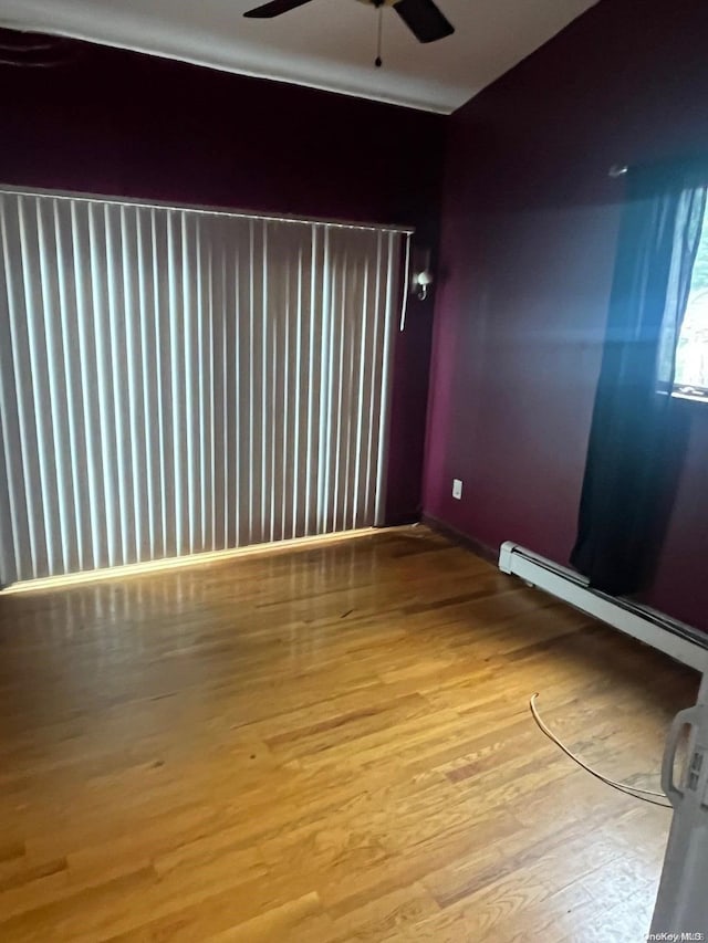 empty room with light hardwood / wood-style flooring, ceiling fan, and a baseboard heating unit