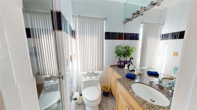 bathroom featuring an enclosed shower, vanity, toilet, and tile walls