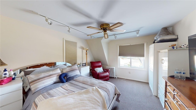 carpeted bedroom with radiator heating unit, rail lighting, and ceiling fan