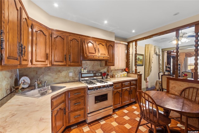 kitchen featuring decorative backsplash, sink, ceiling fan, and white gas range oven