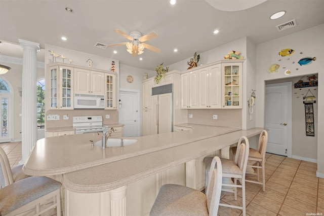 kitchen featuring ceiling fan, sink, a kitchen breakfast bar, kitchen peninsula, and white appliances