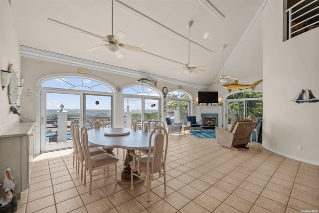 48 S Old Neck Rd, Center Moriches, NY 11934 - dining space featuring ornamental molding, a warm lit fireplace, light tile patterned floors, a ceiling fan, and high vaulted ceiling