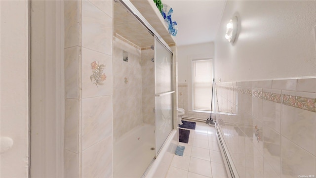 bathroom with tile patterned floors, enclosed tub / shower combo, tile walls, and toilet