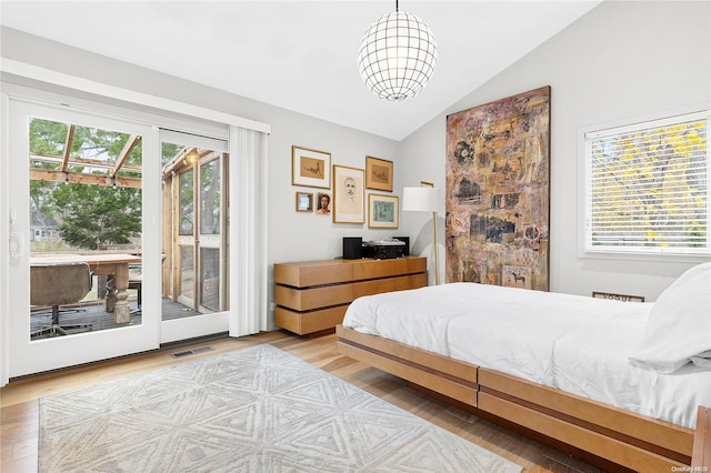 bedroom featuring vaulted ceiling, access to exterior, multiple windows, and light wood-type flooring