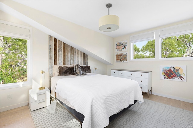 bedroom with multiple windows and light hardwood / wood-style flooring