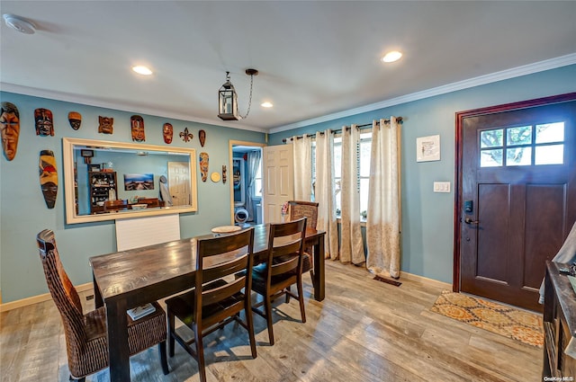 dining space with light hardwood / wood-style floors, a wealth of natural light, and crown molding