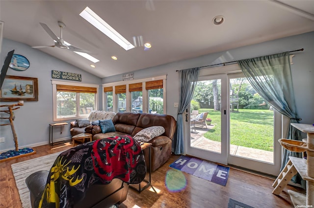 living room featuring light hardwood / wood-style floors, ceiling fan, a healthy amount of sunlight, and vaulted ceiling with skylight