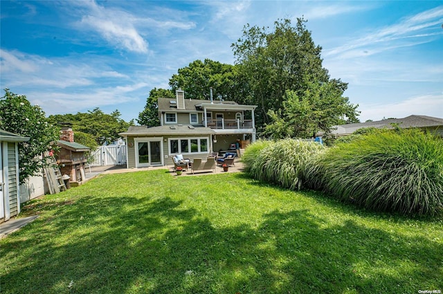 back of property with a patio area, a yard, and a balcony