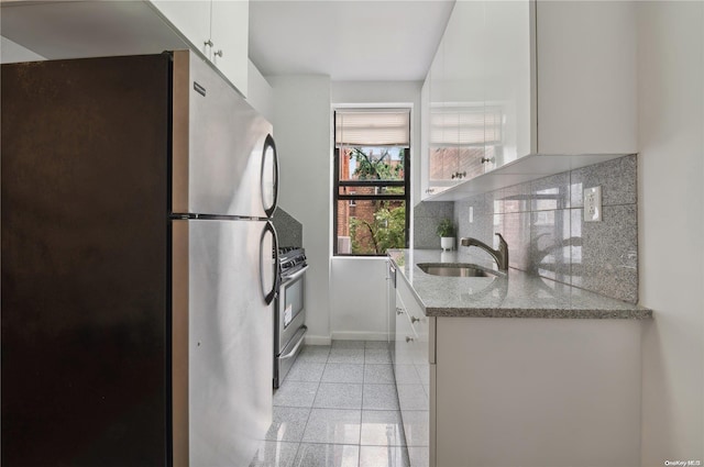 kitchen with white cabinetry, sink, decorative backsplash, light tile patterned flooring, and appliances with stainless steel finishes