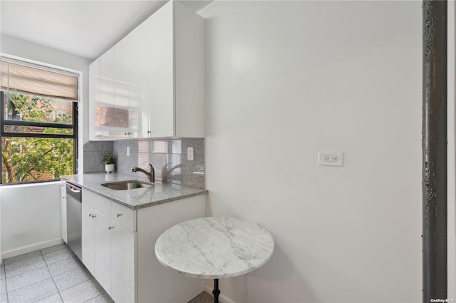 kitchen featuring dishwasher, white cabinets, sink, light stone countertops, and tasteful backsplash