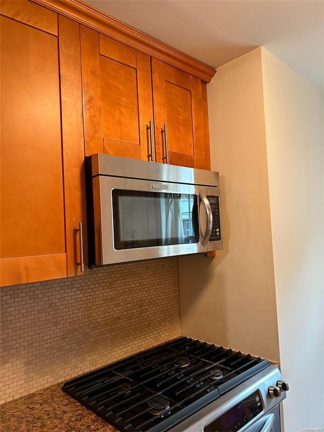 kitchen with stainless steel appliances, dark stone counters, and tasteful backsplash