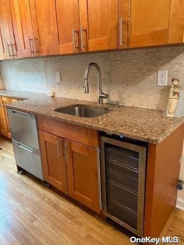 kitchen featuring light stone countertops, backsplash, light hardwood / wood-style flooring, and beverage cooler