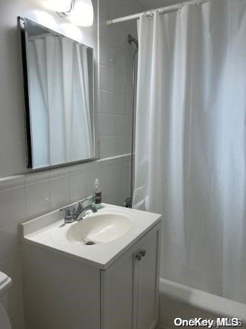 full bathroom with vanity, backsplash, shower / bath combination with curtain, toilet, and tile walls