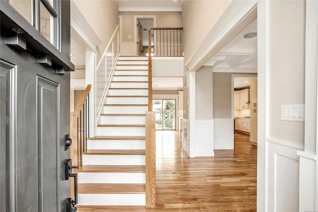 stairway featuring beamed ceiling, wood-type flooring, crown molding, and coffered ceiling