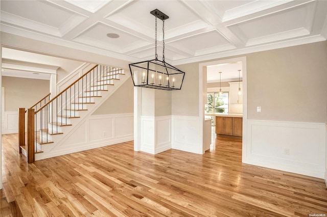 unfurnished dining area with beamed ceiling, a chandelier, coffered ceiling, and hardwood / wood-style flooring