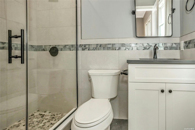 bathroom featuring walk in shower, vanity, toilet, and tile walls