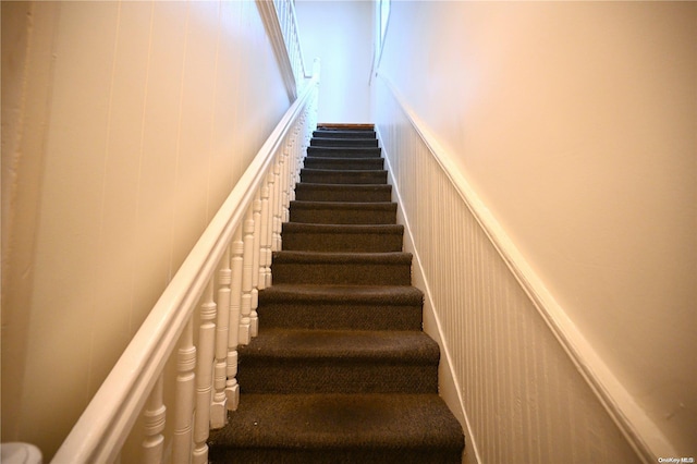 staircase featuring wooden walls